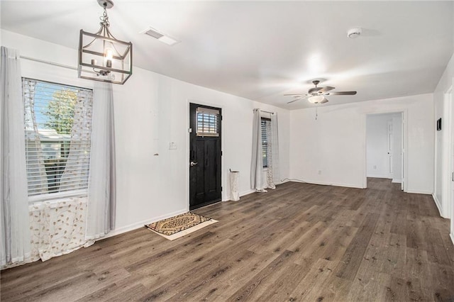 entrance foyer featuring ceiling fan with notable chandelier and dark wood-type flooring