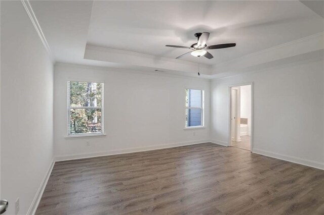 spare room with dark hardwood / wood-style floors, ceiling fan, crown molding, and a tray ceiling