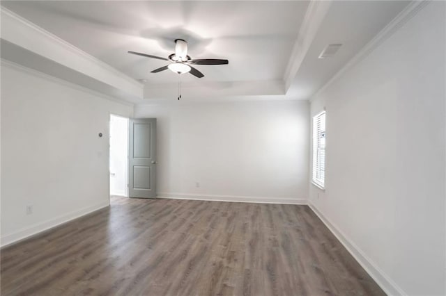 empty room featuring dark hardwood / wood-style floors, ceiling fan, crown molding, and a tray ceiling