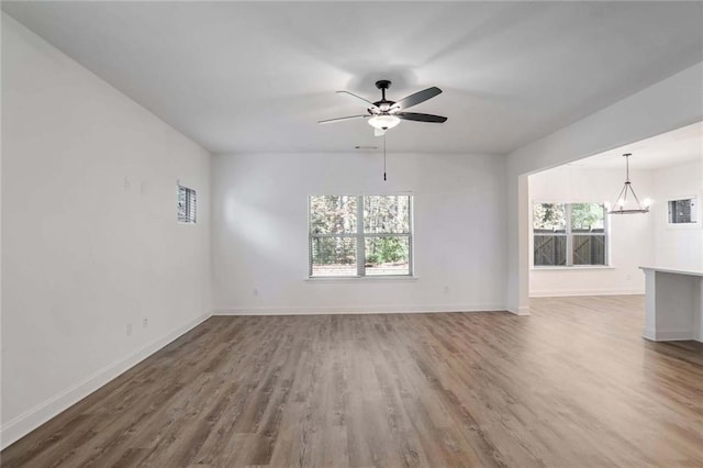 unfurnished living room featuring hardwood / wood-style flooring and ceiling fan with notable chandelier