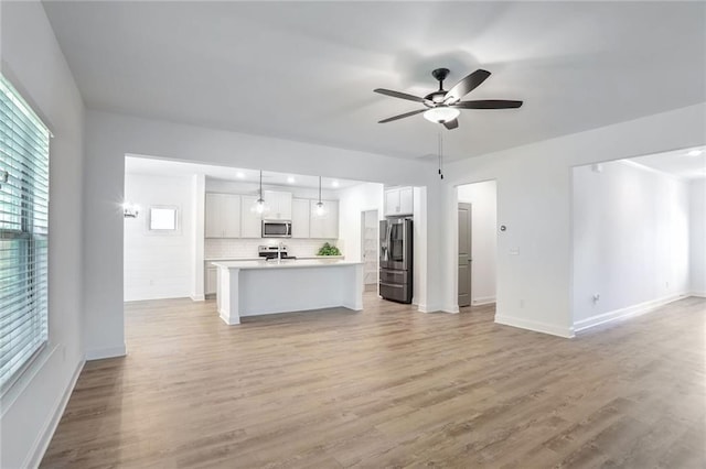 unfurnished living room with light wood-type flooring and ceiling fan