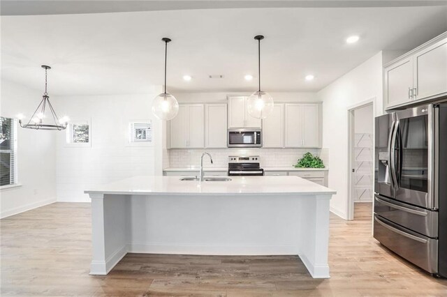 kitchen featuring white cabinets, a kitchen island with sink, sink, and appliances with stainless steel finishes