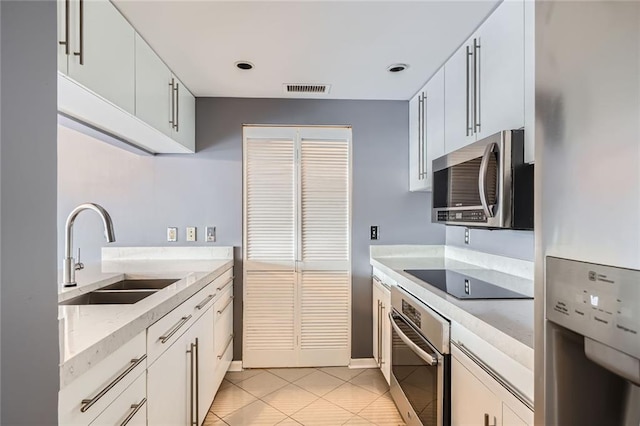 3481 Lakeside Dr NE Unit 1107, Atlanta, GA 30326 - kitchen featuring stainless steel appliances, a sink, light tile patterned floors, white cabinetry, and light stone counters