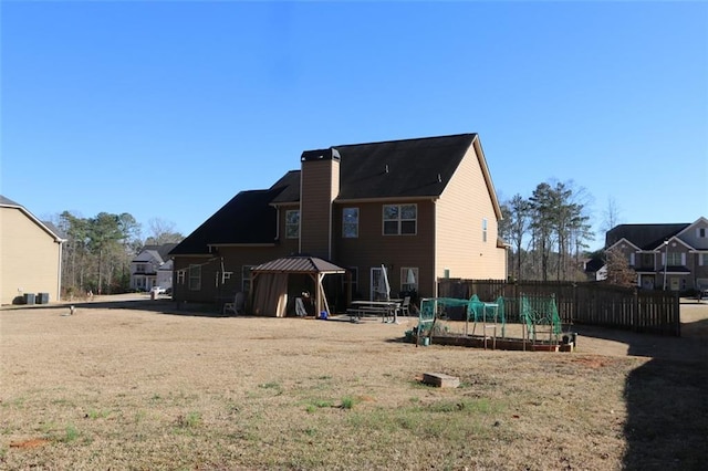 back of house with a garden, a chimney, and fence