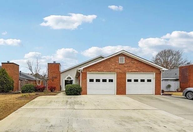 view of front of home featuring driveway, a chimney, fence, and brick siding