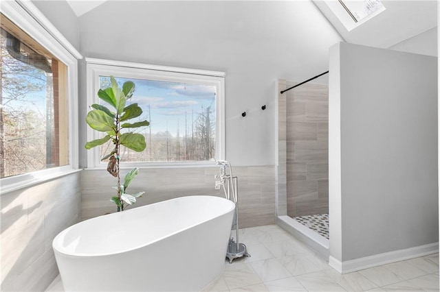 bathroom with tile walls, plenty of natural light, lofted ceiling with skylight, and shower with separate bathtub