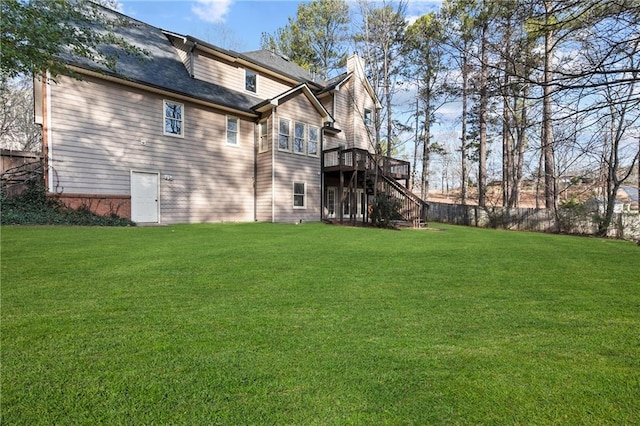 rear view of house featuring a deck and a lawn