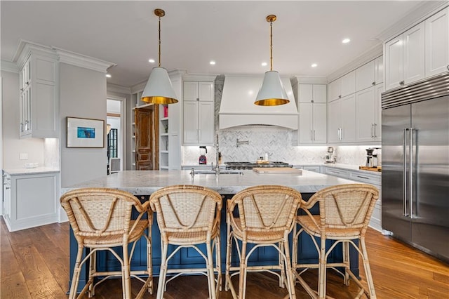 6515 Ashbourne Ct, Suwanee, GA 30024 - kitchen with built in refrigerator, custom range hood, white cabinetry, hardwood / wood-style flooring, and decorative backsplash