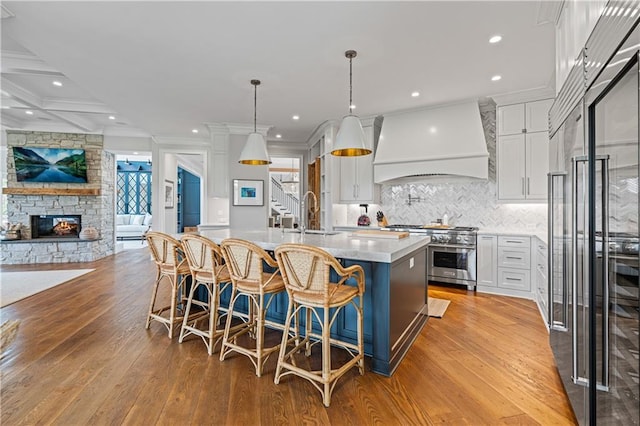 6515 Ashbourne Ct, Suwanee, GA 30024 - kitchen with premium range hood, high quality appliances, a sink, a fireplace, and light wood-style floors