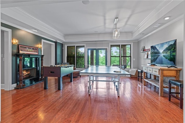 6515 Ashbourne Ct, Suwanee, GA 30024 - game room with wood finished floors, a tray ceiling, a lit fireplace, french doors, and ornamental molding
