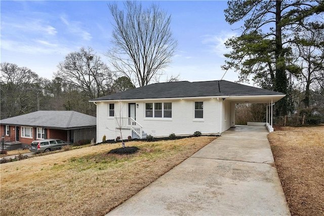 ranch-style home with concrete driveway, an attached carport, a front yard, and brick siding