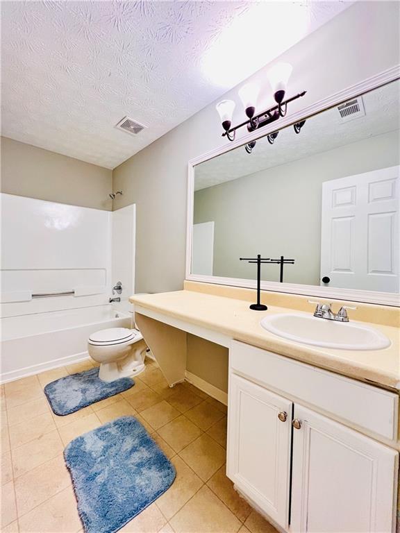 full bathroom with tile patterned floors, toilet,  shower combination, a textured ceiling, and vanity