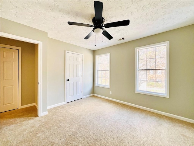 unfurnished bedroom with carpet flooring, a textured ceiling, and ceiling fan