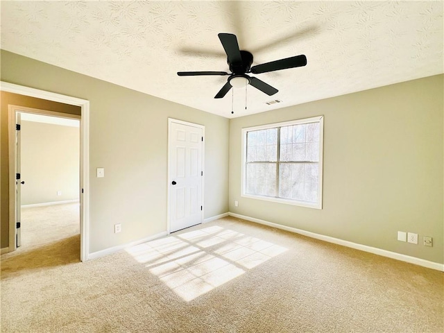 unfurnished bedroom with light carpet, a textured ceiling, and ceiling fan