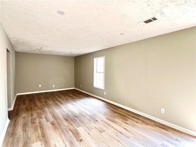 empty room featuring hardwood / wood-style flooring and a textured ceiling