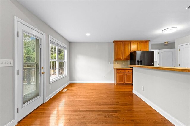 2443 High Meadows Ct, Conyers, GA 30094 - kitchen featuring black fridge with ice dispenser, recessed lighting, baseboards, light wood-style flooring, and brown cabinetry
