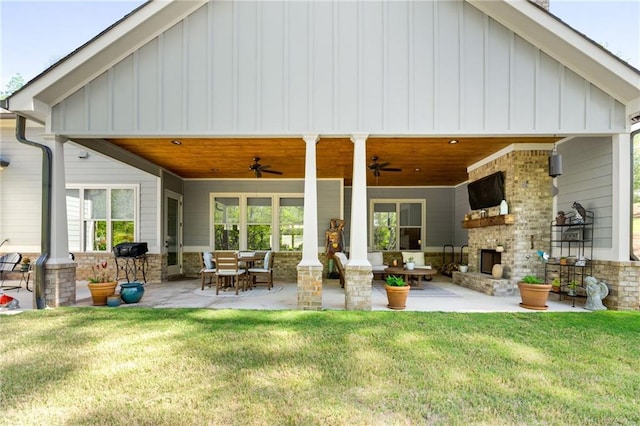 131 Quiet Cove Way, Monticello, GA 31064 - back of house featuring exterior fireplace, ceiling fan, board and batten siding, a patio area, and a yard