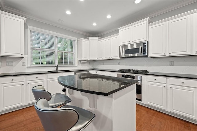 2873 Overlook Way NE, Atlanta, GA 30324 - kitchen featuring appliances with stainless steel finishes, crown molding, a breakfast bar area, white cabinetry, and recessed lighting