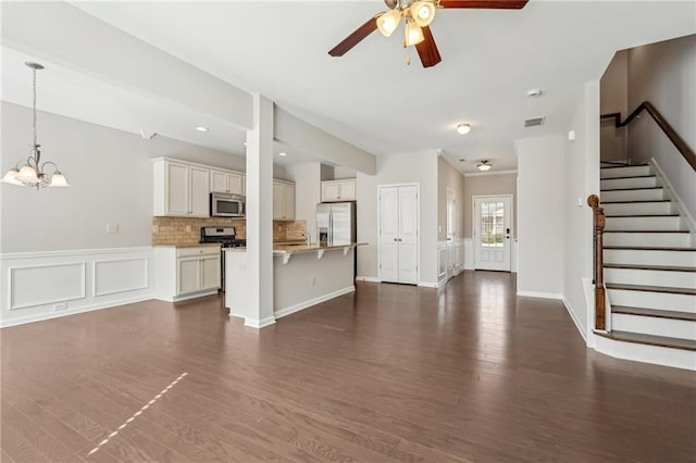 2785 Maple Park Pl, Cumming, GA 30041 - unfurnished living room with stairs, dark wood finished floors, a decorative wall, wainscoting, and ceiling fan with notable chandelier