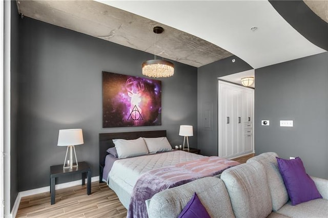 bedroom with a chandelier and light wood-type flooring