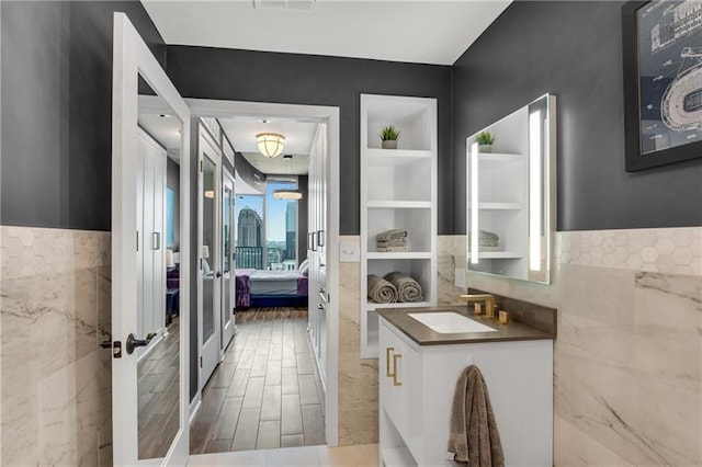 bathroom with built in shelves, sink, and tile walls