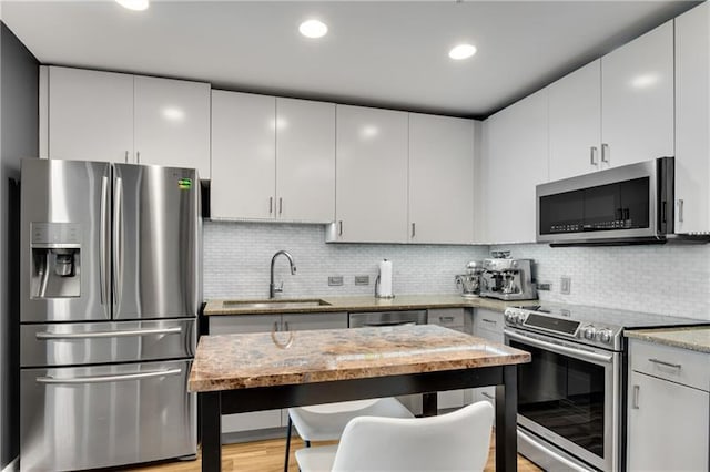 kitchen with appliances with stainless steel finishes, backsplash, white cabinetry, and sink