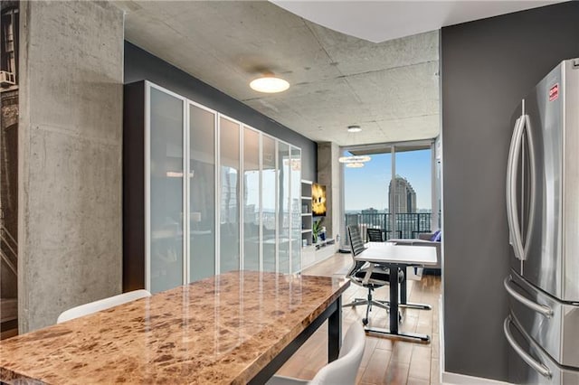 kitchen featuring stainless steel fridge, a wall of windows, and light hardwood / wood-style floors