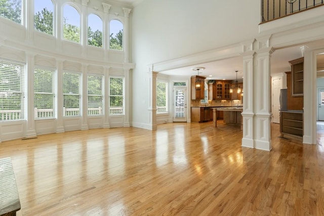 1565 Briergate Dr, Duluth, GA 30097 - unfurnished living room featuring a towering ceiling, ornate columns, and light wood finished floors