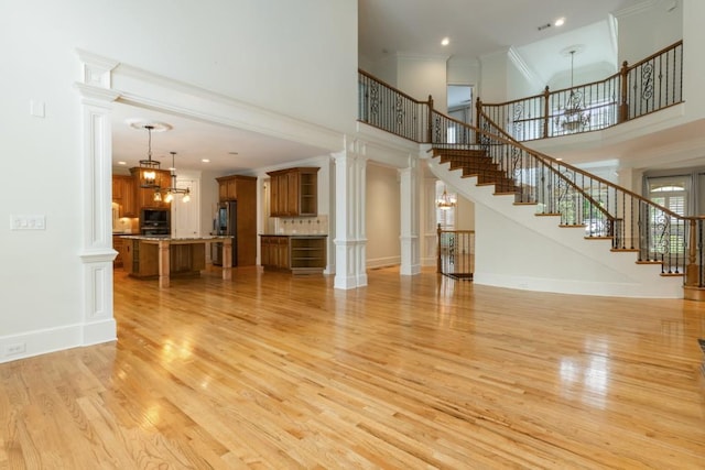 1565 Briergate Dr, Duluth, GA 30097 - unfurnished living room featuring a high ceiling, light wood finished floors, ornamental molding, stairway, and a chandelier