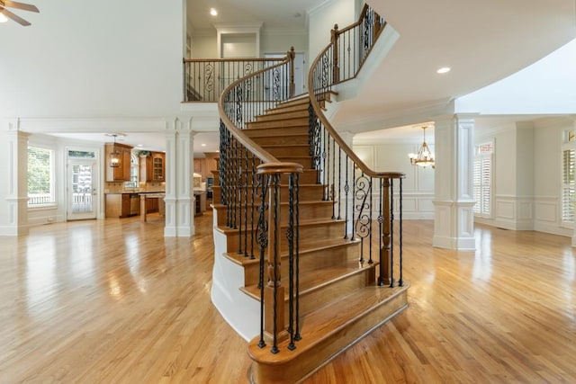 1565 Briergate Dr, Duluth, GA 30097 - stairway featuring a decorative wall, crown molding, wood finished floors, a high ceiling, and decorative columns
