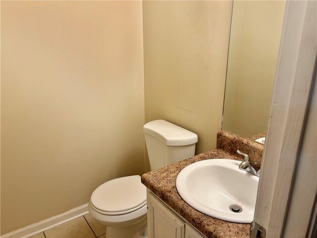 bathroom with toilet, vanity, and tile patterned floors