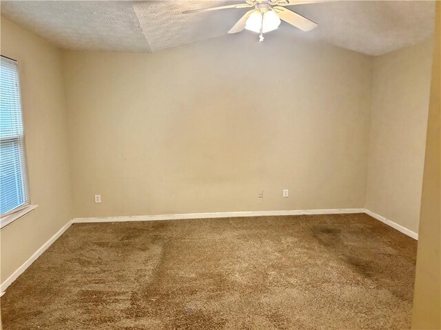 carpeted empty room with lofted ceiling, a textured ceiling, and ceiling fan