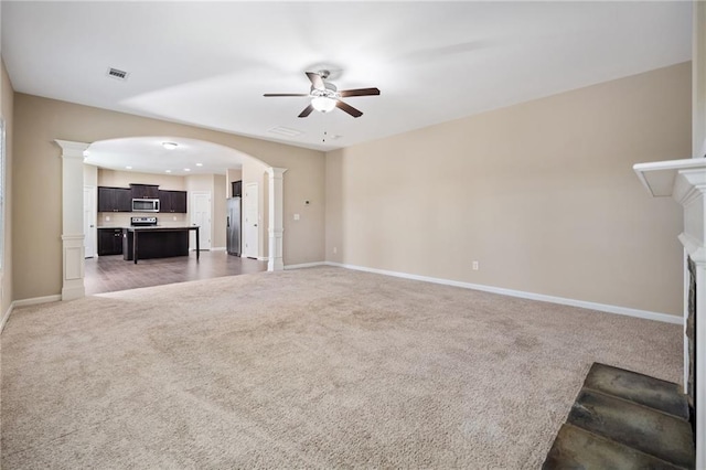 unfurnished living room with ceiling fan, dark carpet, and ornate columns