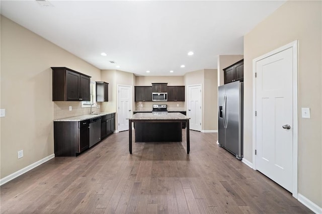 kitchen featuring dark brown cabinetry, a center island, stainless steel appliances, tasteful backsplash, and sink