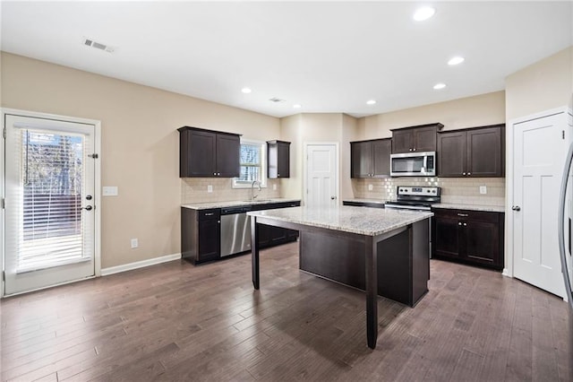 kitchen featuring stainless steel appliances, a center island, dark brown cabinetry, and dark wood-type flooring