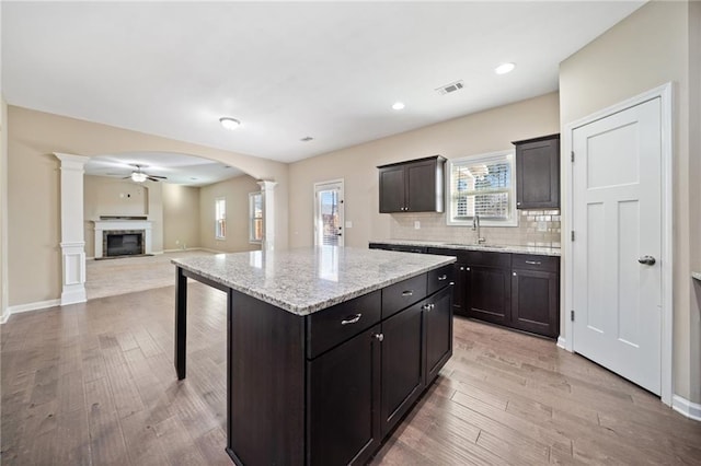 kitchen featuring a kitchen island, sink, a kitchen breakfast bar, and ornate columns