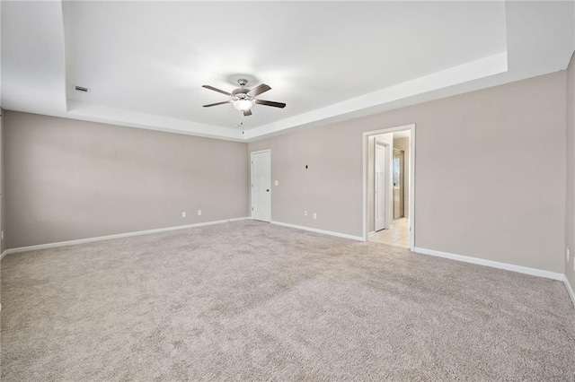 carpeted empty room featuring ceiling fan and a tray ceiling