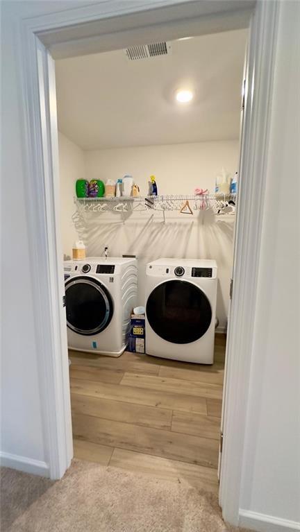 laundry area featuring washing machine and clothes dryer and light wood-type flooring