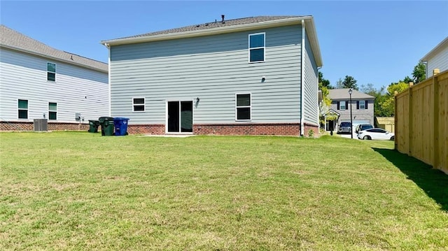 rear view of property with central AC unit and a lawn