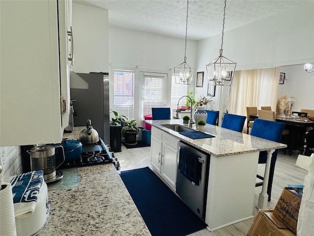 kitchen featuring sink, an island with sink, a kitchen breakfast bar, stainless steel appliances, and white cabinets