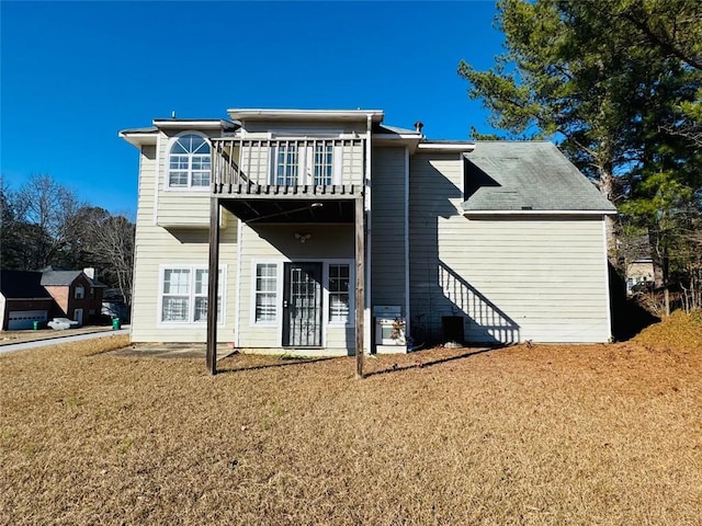 rear view of house with a balcony and a lawn