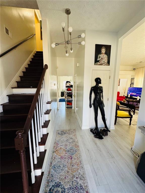 entryway with a textured ceiling, hardwood / wood-style flooring, and a notable chandelier