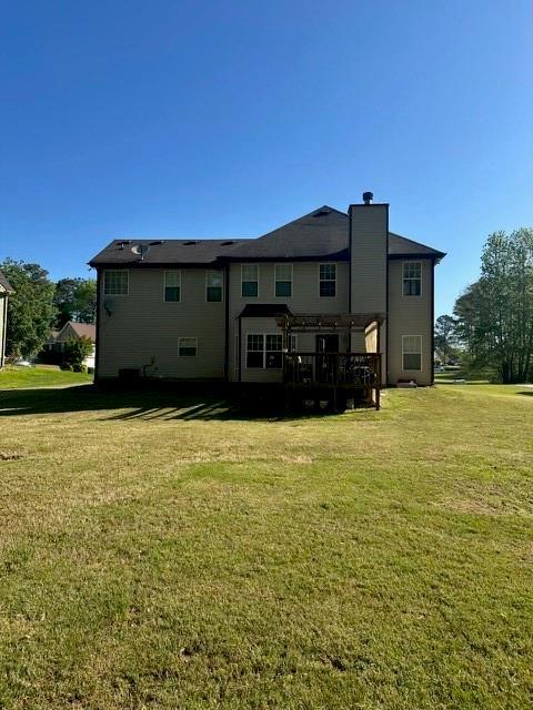 back of property featuring a lawn and a chimney