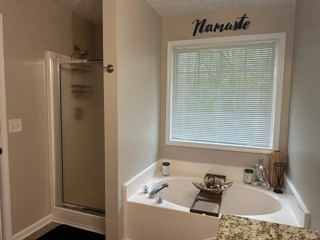 full bath with a shower stall, a bath, a healthy amount of sunlight, and a textured ceiling