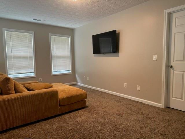 living area featuring a textured ceiling, visible vents, baseboards, and carpet