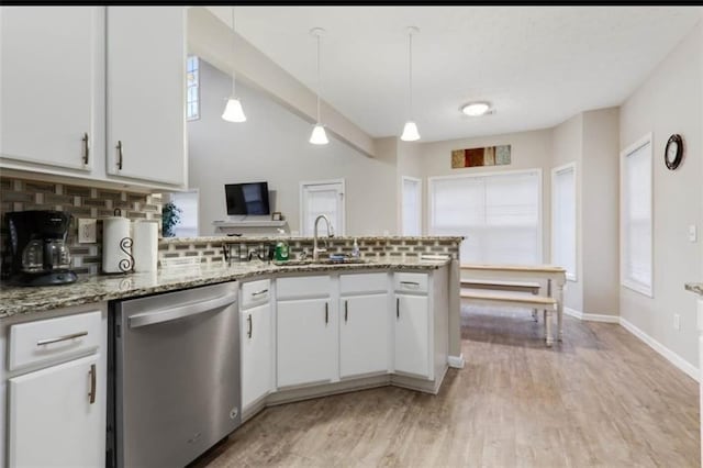 kitchen featuring stainless steel dishwasher, a peninsula, white cabinets, a sink, and backsplash