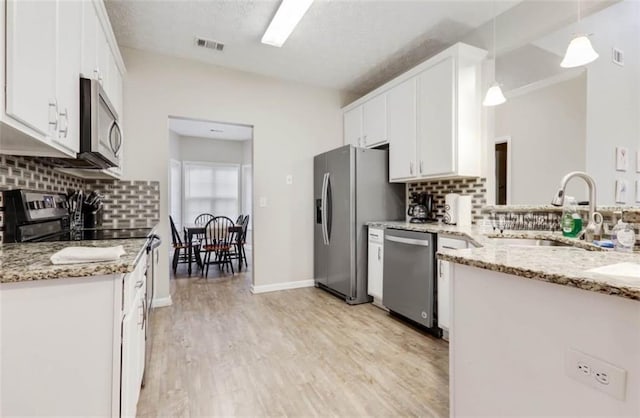 kitchen featuring tasteful backsplash, white cabinetry, a sink, and appliances with stainless steel finishes