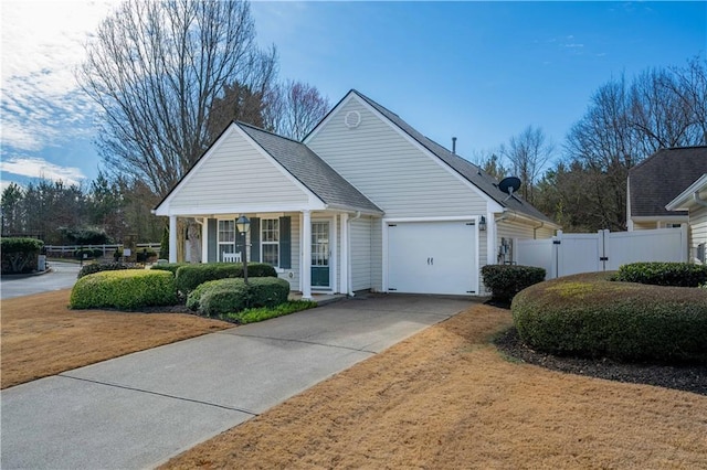 view of front of house featuring roof with shingles, an attached garage, a gate, fence, and driveway