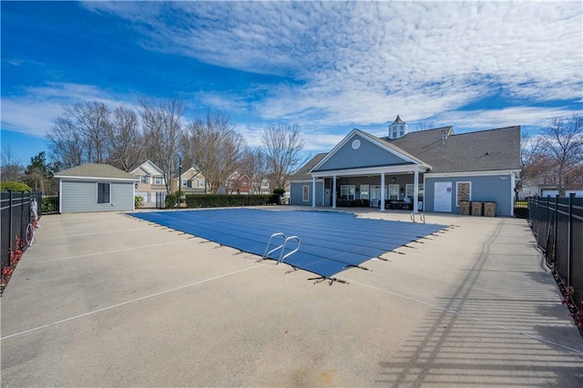 community pool featuring fence, an outbuilding, and a patio