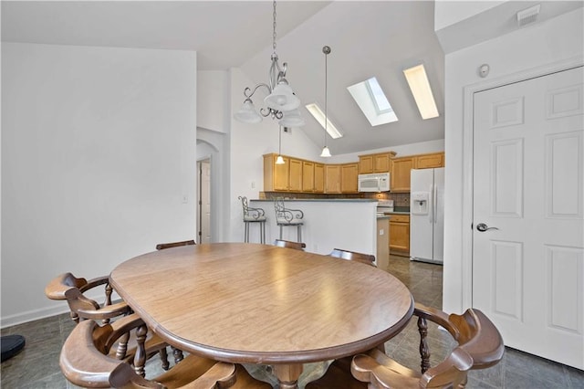 dining area featuring arched walkways, a skylight, visible vents, high vaulted ceiling, and dark tile patterned floors